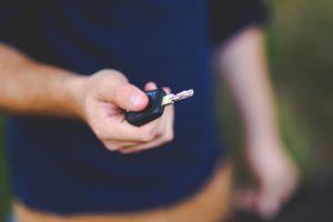 a man with dark blue sweater holding a car key